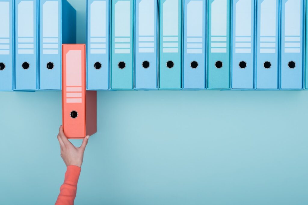 woman's hand removing a red file from a line of blue folder