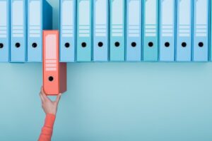 woman's hand removing a red file from a line of blue folder
