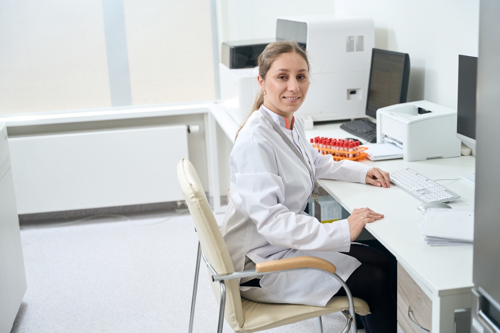 woman sitting in a medical lab next to a printer